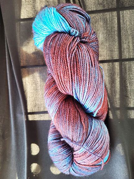 A skein of burgandy/sky blue dyed sock yarn