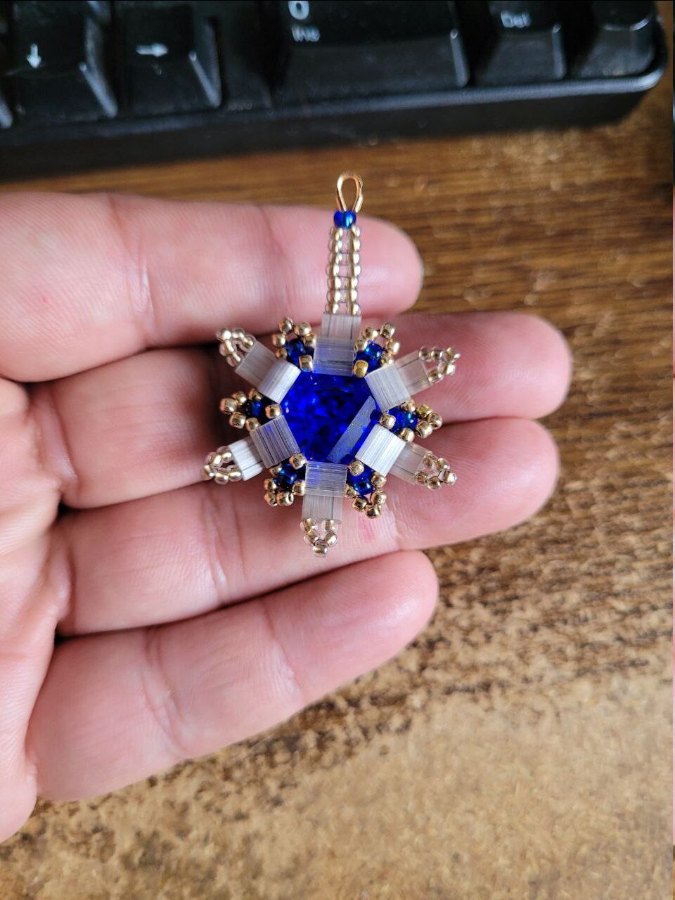 A 16x14mm Crystal Passions® prismatic hexagon—Majestic Blue foil back—encased in six Tila beads. 11/0 and 8/0 Toho beads accentuate the piece. If you look closely, you can see the thread in the Tila beads, an error on my part because I did have white beading thread but didn't think of it until waaaay later XD